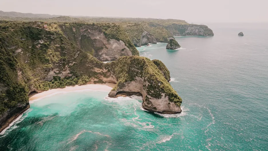 An Aerial view of blue ocean water meeting the land of Bali.