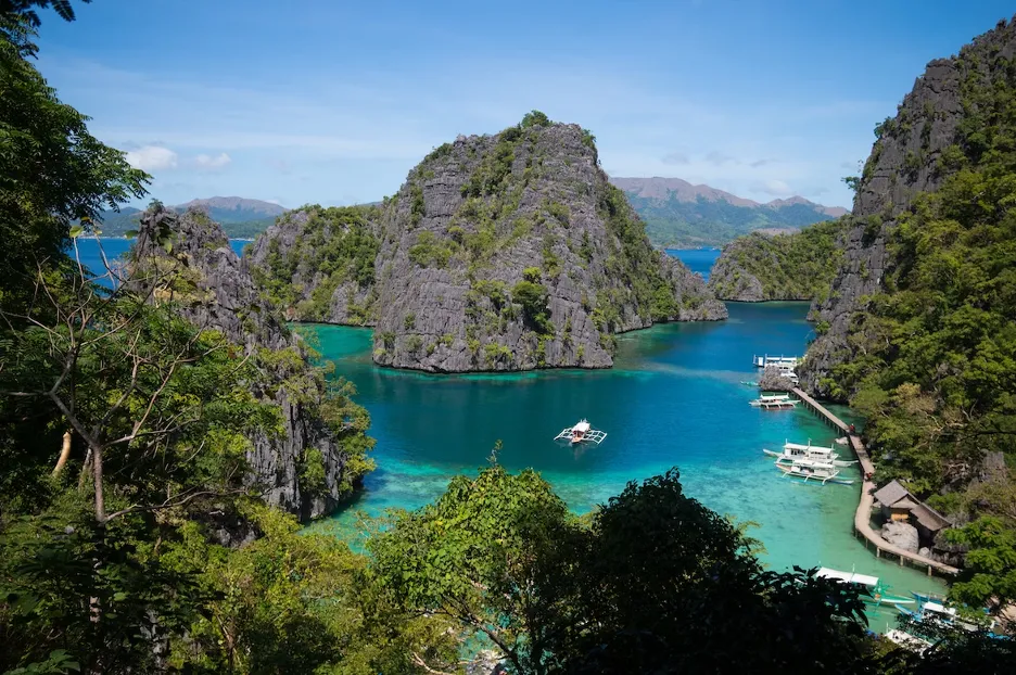Mountains with greenery and boats in the ocean in the Philippines.